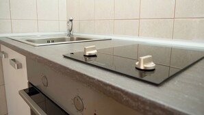 A modern kitchen with a built-in gas stove, a stainless steel sink, and a white tiled backsplash. - Apartments Vlade (Primosten)