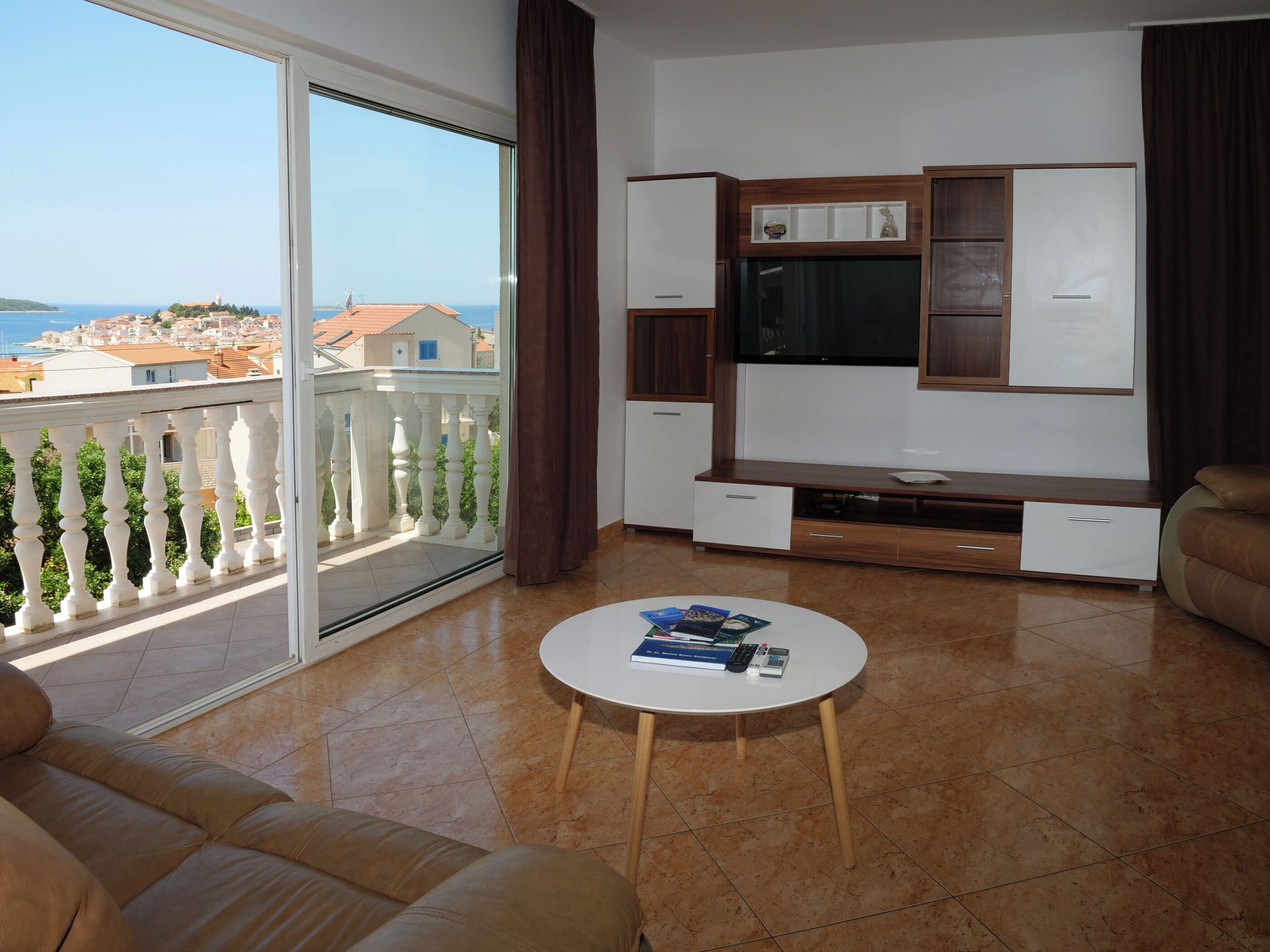 A living room with a balcony, a sofa, a coffee table, and a TV stand.