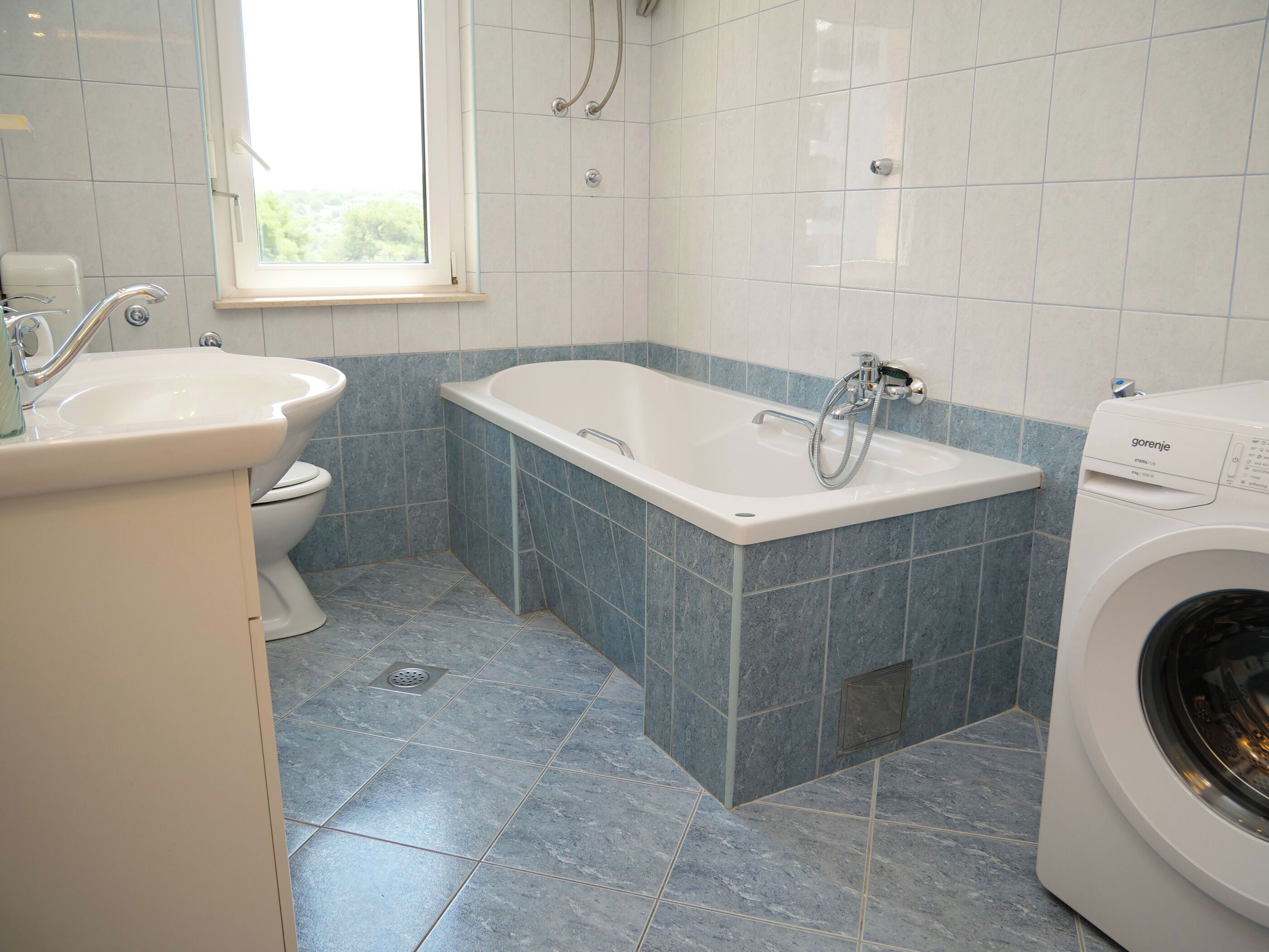 A bathroom with a bathtub, a sink, a toilet, and a washing machine.