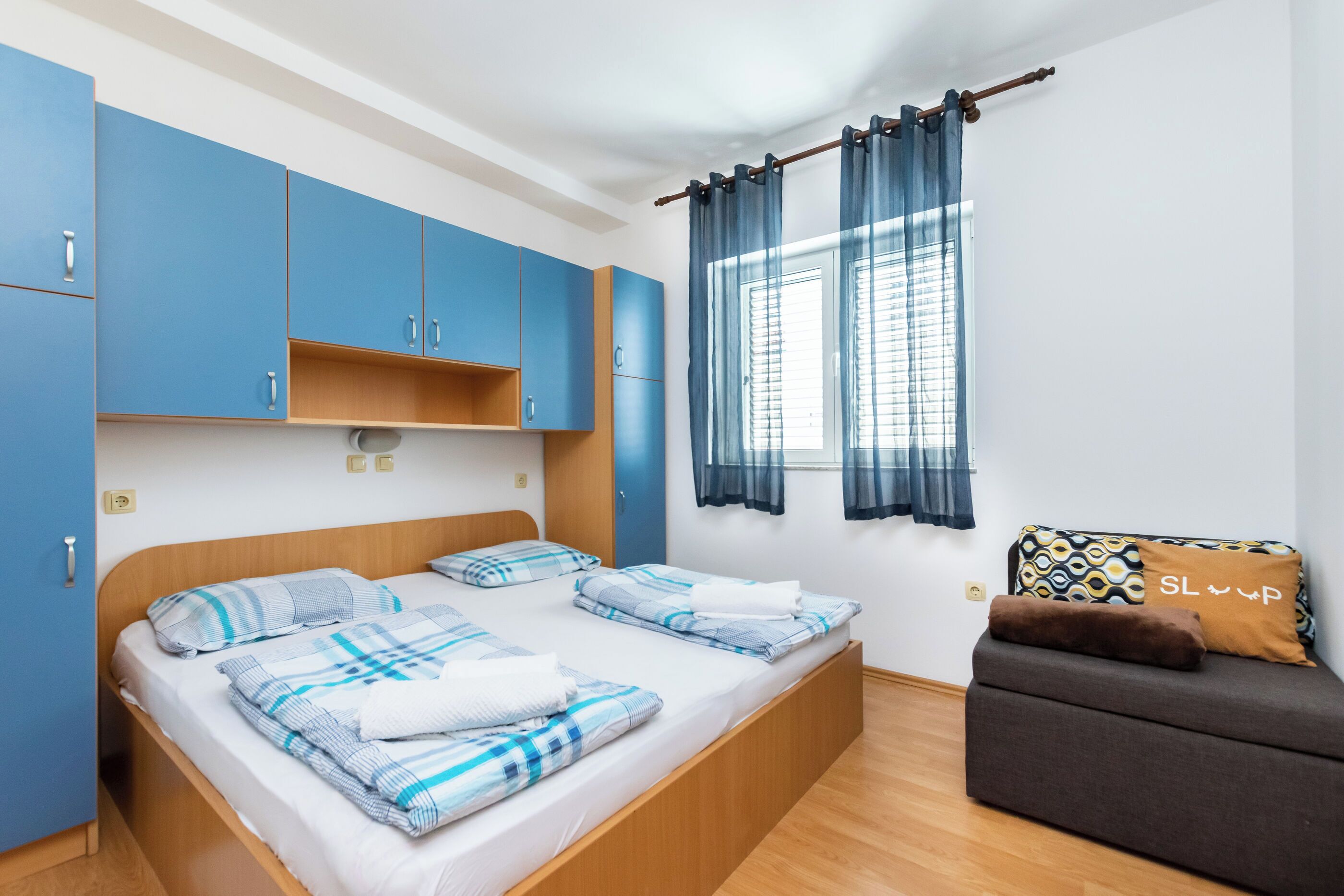 A bedroom with a bed, a sofa, and a window with curtains.