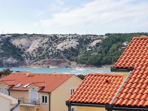 A coastal village with terracotta-roofed houses, a clear view of the sea, and a hilly backdrop. - Apartments Miranda (Lopar)