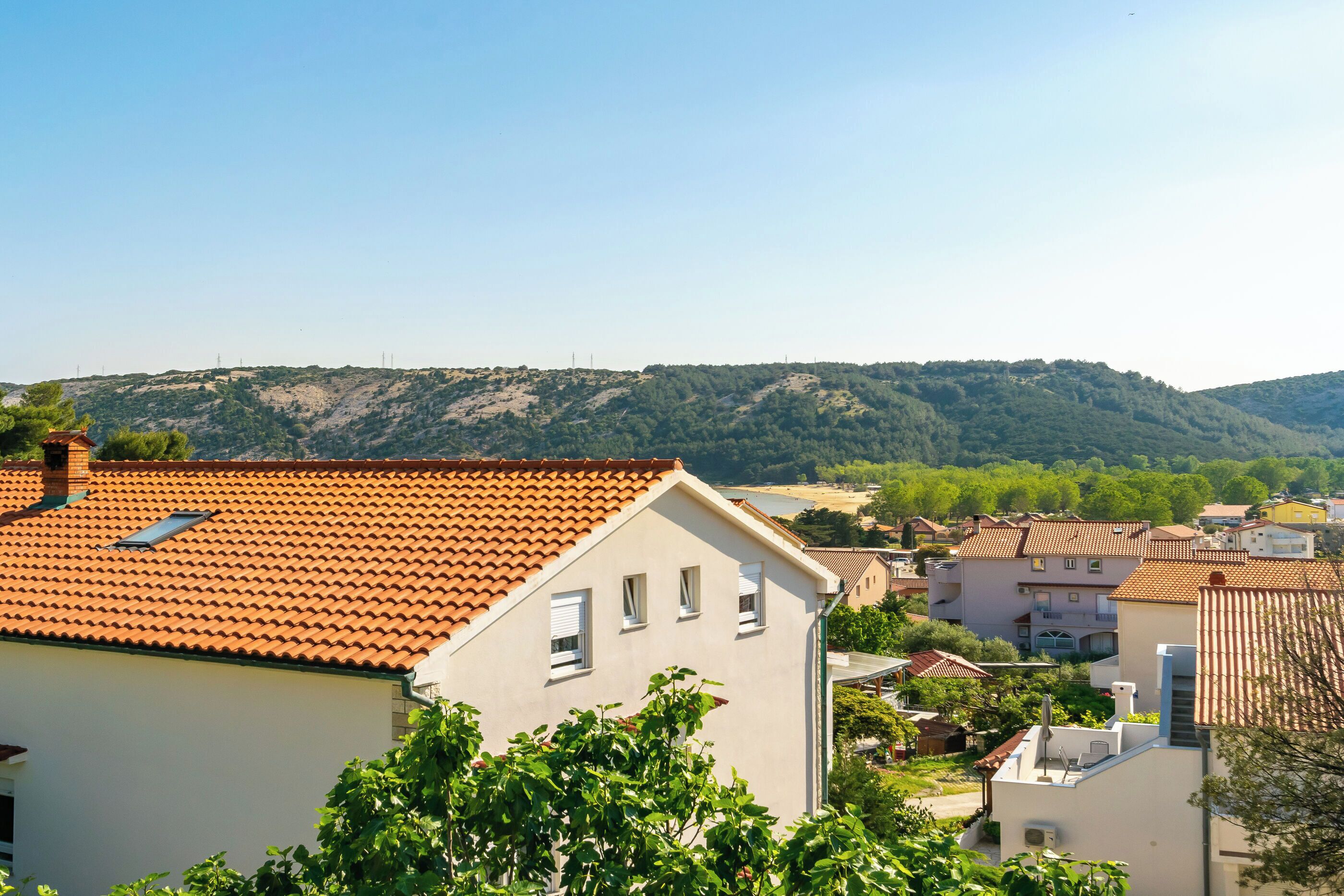 Área residencial com casas de paredes brancas e telhados de telha vermelha.