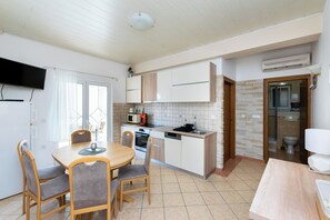 A compact kitchen with a dining area, a built-in oven, and a microwave. - Apartments Miranda (Lopar)