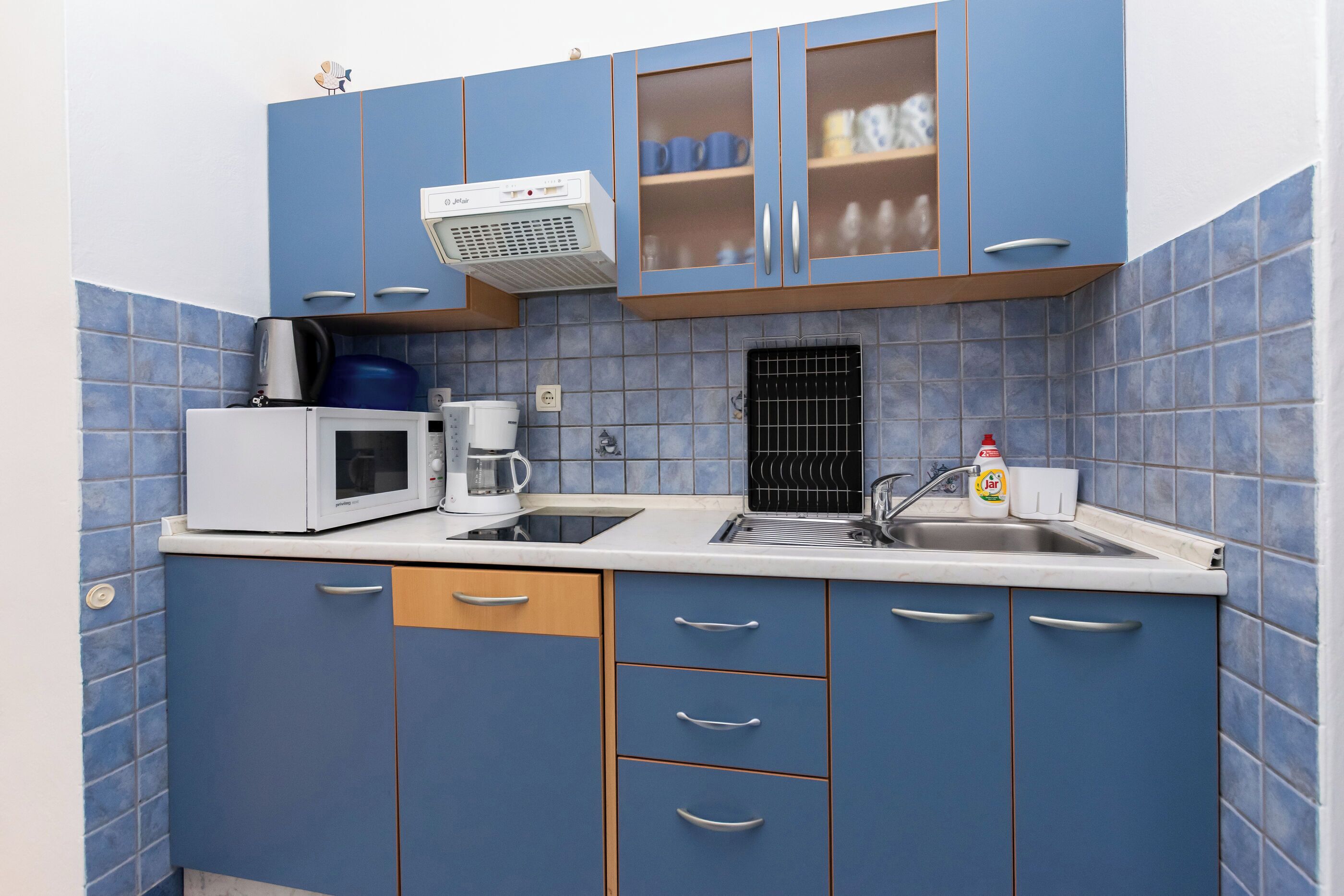 A kitchen with blue cabinets, a microwave, a coffee maker, and a sink.