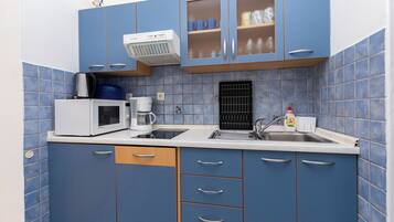 A kitchen with blue cabinets, a microwave, a coffee maker, and a sink.