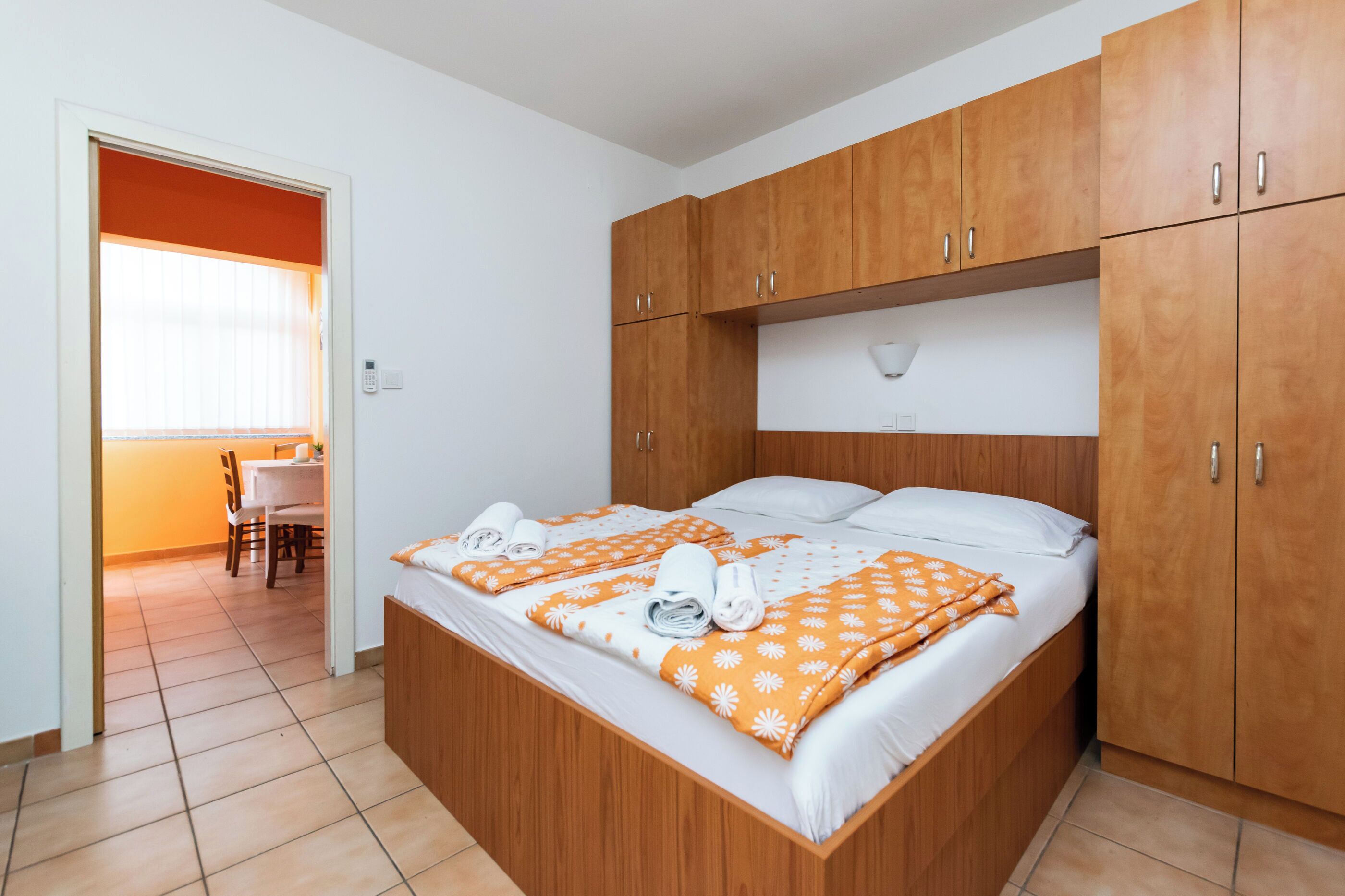 A bedroom with a wooden bed, white bedding, and a wooden wardrobe.