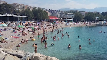 Uma praia movimentada com pessoas se banhando e nadando.