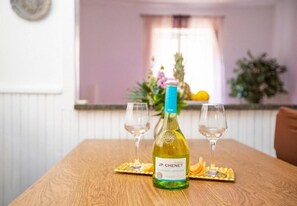 A bottle of JP. Chenet wine on a wooden table with two wine glasses. - Apartment Roko in Center (Split)