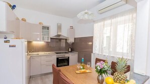 Eine moderne Küche mit Esstisch aus Holz, Stühlen und einer Obstauslage.