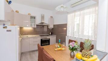 Uma cozinha moderna com uma mesa de jantar de madeira, cadeiras e uma exposição de frutas.