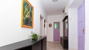 Ein Flur mit einer dunklen Holztruhe, einer Topfpflanze und einem Gemälde an der Wand.