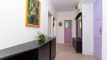 Um corredor com um console de madeira escura, um vaso de planta e um quadro na parede.