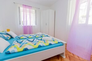 Une chambre à coucher avec un lit, une armoire, une fenêtre avec des rideaux et une table de chevet.