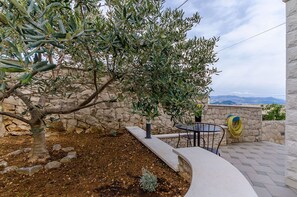 A stone wall, a small tree, and a table with chairs in a courtyard.