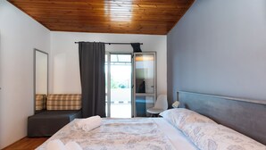 A bedroom with a large bed, a sofa, a chair, and a door leading to an outdoor area. - Apartments Milena (Lopar)