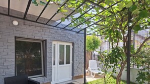 Un patio cubierto con pared de piedra, una puerta, una ventana y mobiliario exterior.
