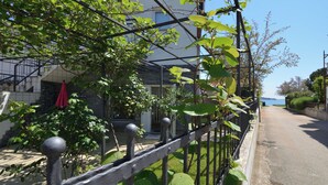 Zona residencial con una calle pavimentada, cerca metálica y vegetación.