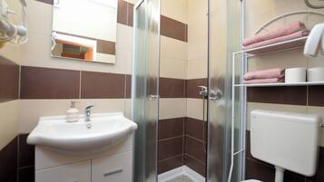 Un baño con cabina de ducha de vidrio, lavabo e inodoro.