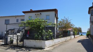 Una calle residencial con casas, un portón y una vista despejada del mar al fondo.