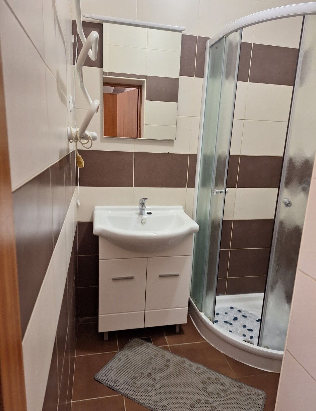 Une salle de bain avec un lavabo, un miroir et une douche.
