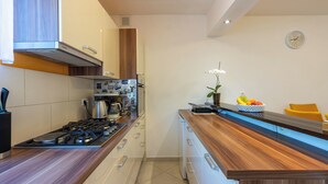 Une cuisine moderne équipée d’une cuisinière à gaz, d’appareils électroménagers en acier inoxydable, de meubles en bois et d’un four encastré.