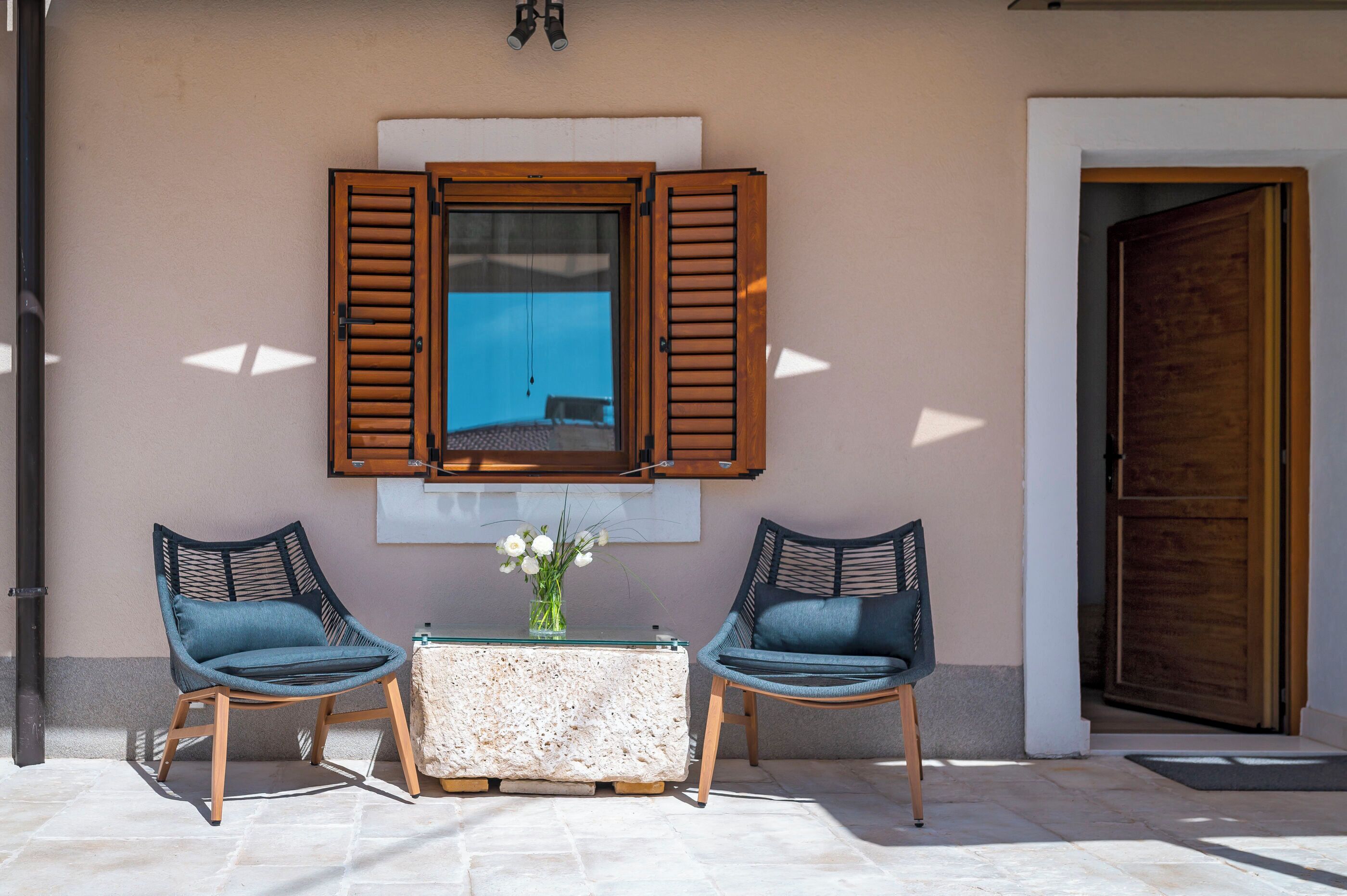 Un espace patio avec deux chaises, une table et un vase de fleurs.