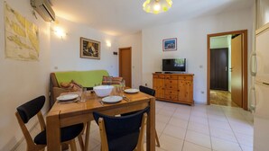 Un coin repas avec une table et des chaises en bois, un téléviseur posé sur un meuble en bois, et une carte accrochée au mur.