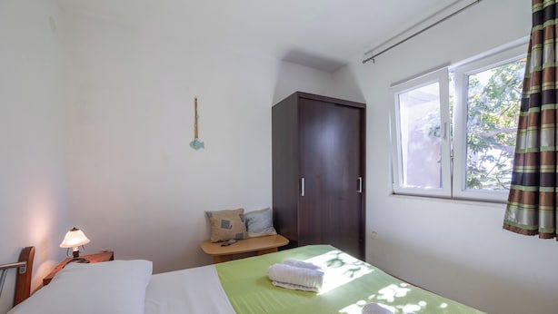 Une chambre à coucher comprenant un lit, une table de chevet, une fenêtre et une armoire.