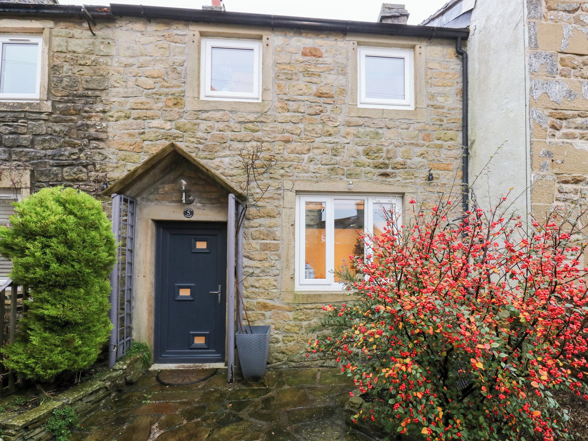 A stone house with a dark blue door, a small porch, and a window with a white frame.