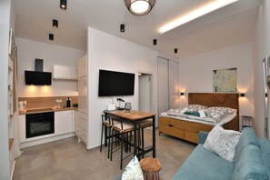 A compact living space with a kitchenette, a dining area, a bed, and a TV mounted on the wall. - Apartment Leprin (Labin)