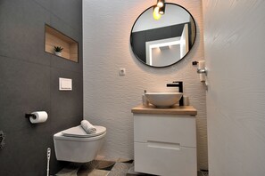 A modern bathroom with a toilet, sink, and mirror. - Apartment Leprin (Labin)