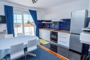 Een moderne keuken met een eethoek, uitzicht door het raam en een wandgemonteerde flatscreen-tv.