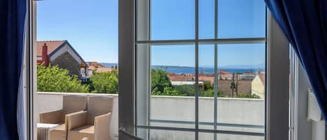 A balcony with wicker furniture and a clear view of the surrounding buildings and landscape.