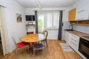 Eine kleine Küche mit Essecke, Holzboden und einem Fernseher über der Arbeitsfläche.