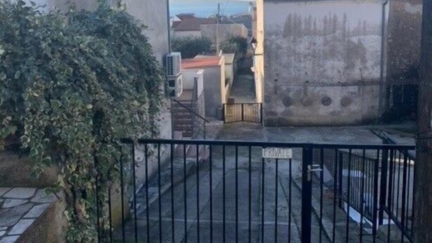 A gated courtyard with a building, a small structure, and a view of the sea. - Apartments Tanjy (Crikvenica)