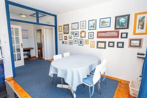 Een kamer met een ronde tafel, stoelen en een vloerkleed.