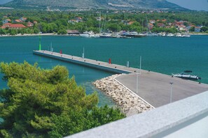 Ein Yachthafen mit vertäuten Booten, eine Mole, die sich ins Wasser erstreckt, und Häuser im Hintergrund.