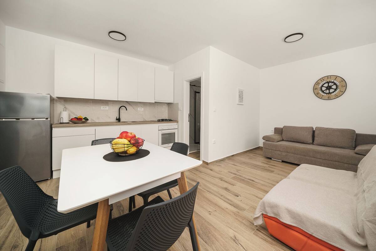 A compact living space with a kitchenette, a dining area with a table and chairs, and a sofa.
