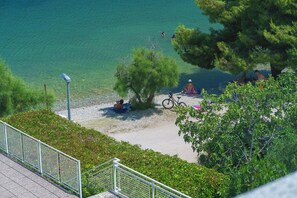 A lakeside area with people relaxing by the water, a bicycle, and a metal railing. - Apartments Picikato (Bilice)