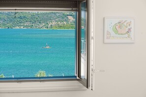 A window with a view of a calm sea and a distant island. - Apartments Picikato (Bilice)