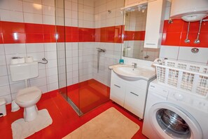 A bathroom with a toilet, sink, and washing machine. - House Levanat (Polaca)