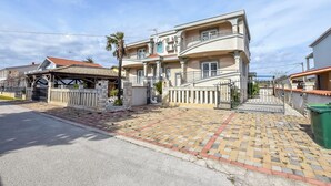 Una casa a due piani con vialetto lastricato e ingresso recintato.
