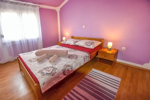 A bedroom with a bed, nightstands, and a window with curtains. - House Levanat (Polaca)