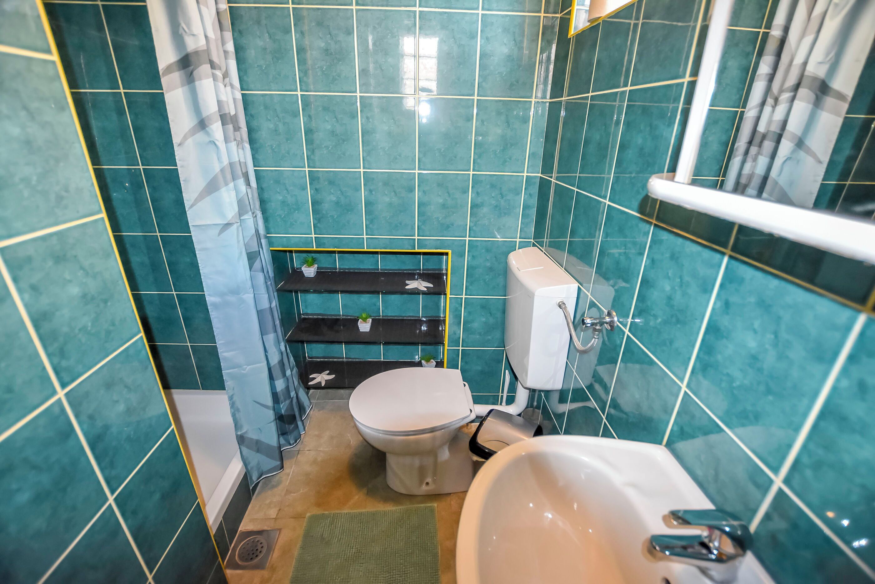 Een compacte badkamer met toilet, wastafel en douche.