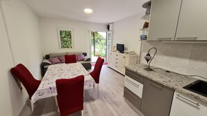 A compact kitchen with a sink, stove, and cabinets. There is a dining area with a table and chairs. - House Maja (Sibenik)