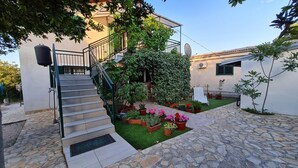 A courtyard with a stone staircase leading to a building, surrounded by potted plants and a small lawn. - House Maja (Sibenik)