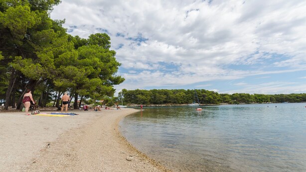 A pebbled beach with trees and a calm lake. - House Maja (Sibenik)