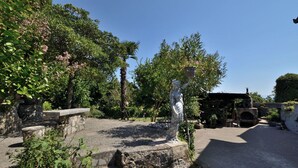 Un jardin agrémenté d’une statue, d’un escalier en pierre et d’une construction en briques.