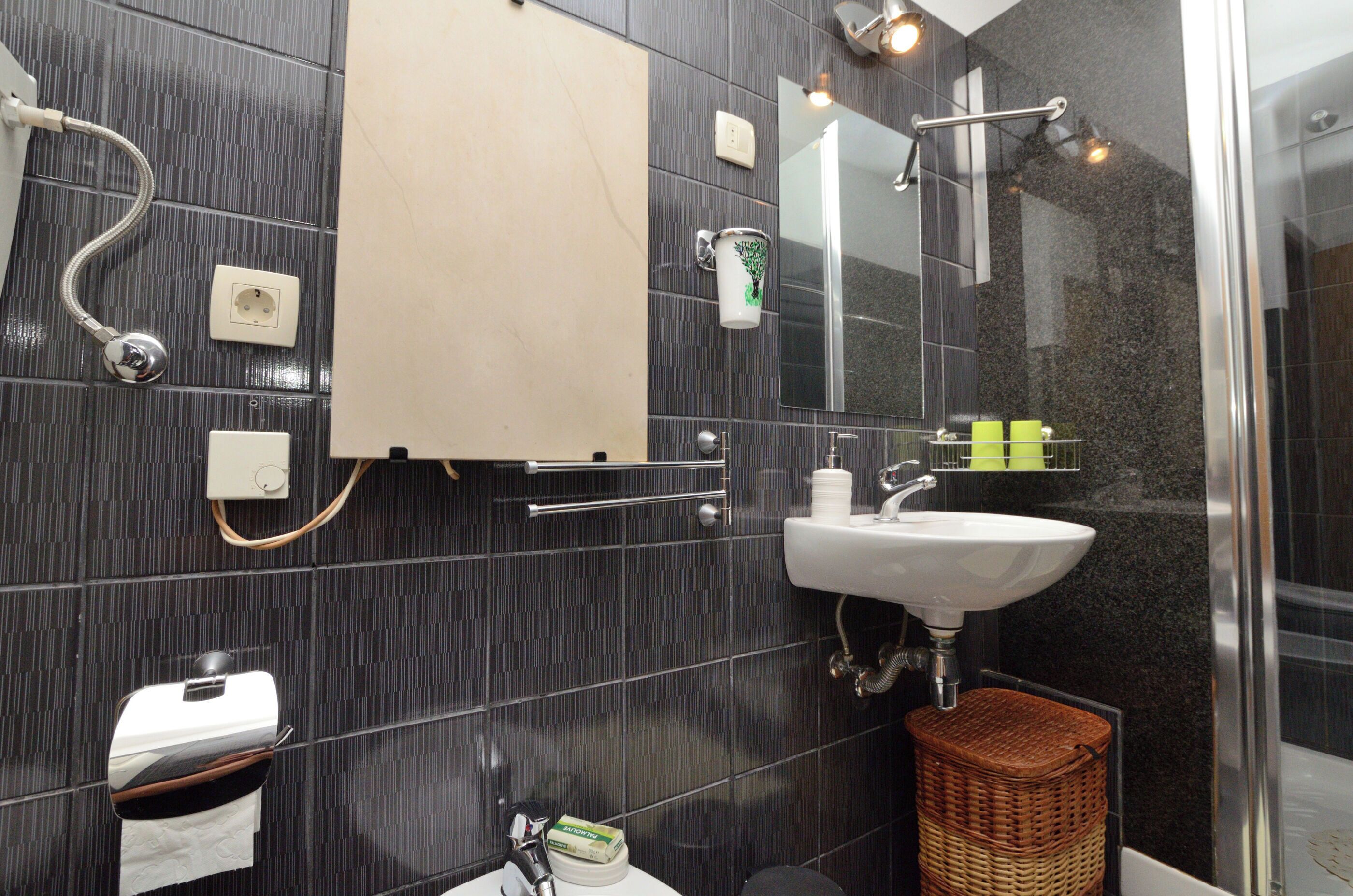 A modern bathroom with a glass shower enclosure, a white sink, and a towel rack.