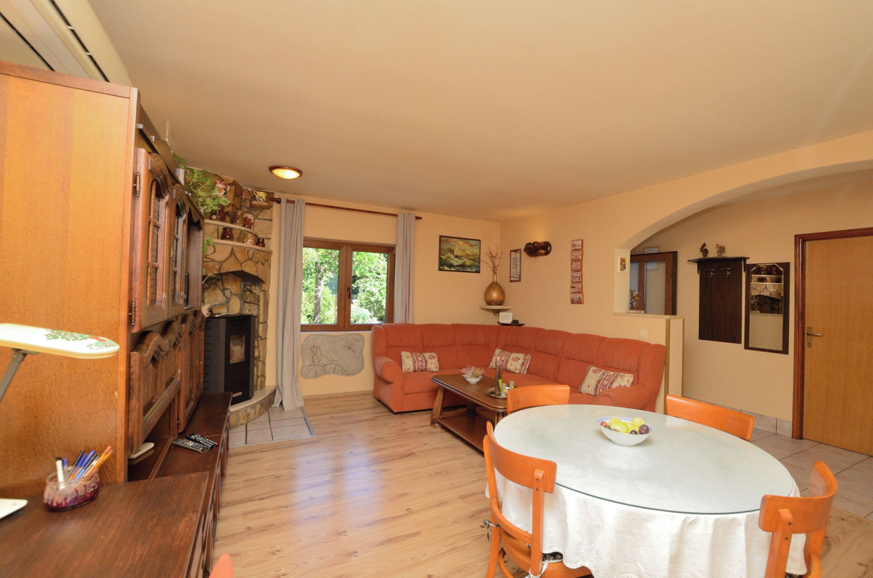 Una sala de estar acogedora con chimenea, un sofá, una mesa de comedor con sillas y una pared de piedra.